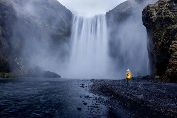 person-wearing-yellow-jacket-standing-mesmerizing-waterfall.jpg